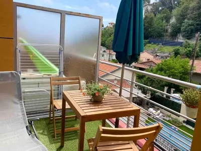 a balcony with a table and chairs and an umbrella at Studio balcon proche mer in Nice