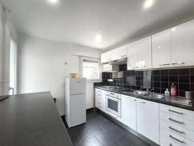 a kitchen with white cabinets and a black counter top at Large T2 50m from the beaches in Nice