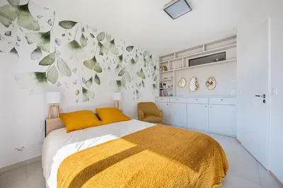 a bedroom with a bed with a yellow blanket at Magnifique T3 wifi, garage et climatisation à 5 min de la plage in Beaulieu-sur-Mer