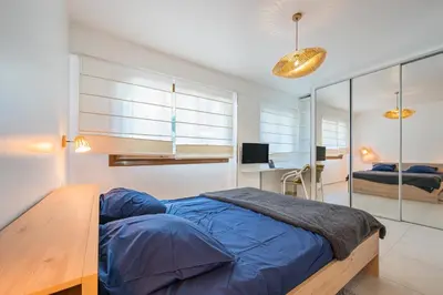 a bed with a yellow pillow and two lamps at Magnifique T3 wifi, garage et climatisation à 5 min de la plage in Beaulieu-sur-Mer