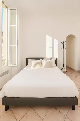 a bedroom with a large bed with white sheets at Grand studio dans le centre ville de Nice in Nice