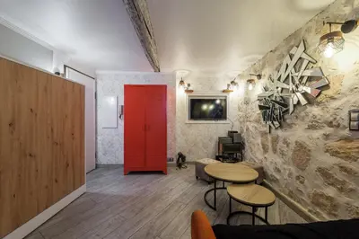 a living room with a red door and two tables at Coquet studio place du pin in Nice