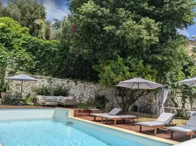 a swimming pool with two chairs and umbrellas next to at Villa Adelaida in Nice