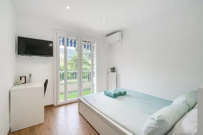 a white bedroom with a bed and a window at Modern apartment, steps from tramway in Nice