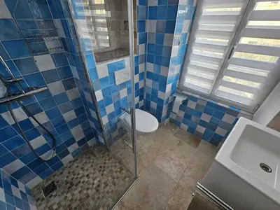 a blue tiled bathroom with a toilet and a sink at appartement maison de village in Cagnes-sur-Mer