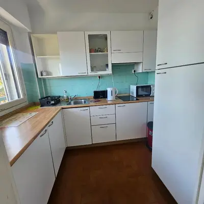 a kitchen with white cabinets and a white refrigerator at Vue mer studio tout équipé in Nice