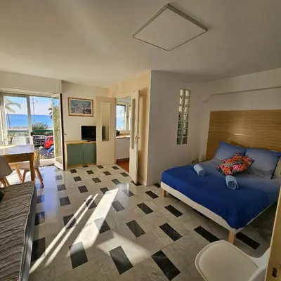 a bedroom with a blue bed and a living room at Vue mer studio tout équipé in Nice