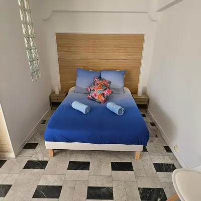 a bed with blue sheets and pillows in a room at Vue mer studio tout équipé in Nice