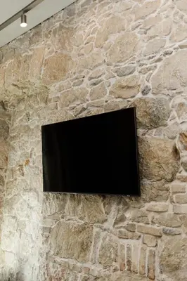 a flat screen tv on a stone wall at Notre Dame Hotel - Self Check-in in Nice