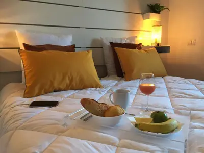 a tray of food and a glass of wine on a bed at Appartement Eze Village proche Monaco fabuleuse vue mer et vieux village in Èze