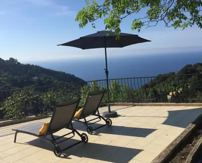 two chairs and an umbrella on a patio at Appartement Eze Village proche Monaco fabuleuse vue mer et vieux village in Èze