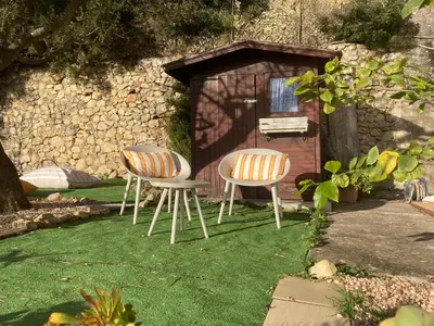 two chairs sitting in the grass in front of a shed at Appartement Eze Village proche Monaco fabuleuse vue mer et vieux village in Èze