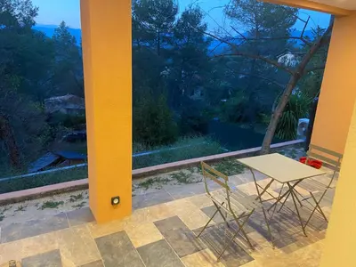 a table and chairs on a porch with a view of the ocean at Appartement T3 dans une villa au calme in Drap