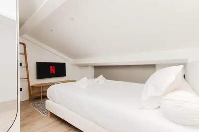 a bedroom with a white bed and a tv at Modern 3BR Duplex Near Nice Port & Old Town | By Airnest in Nice
