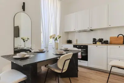 a kitchen with a black table and white cabinets at Fancy 3BR Duplex Near Nice Port & Old Town | By Airnest in Nice