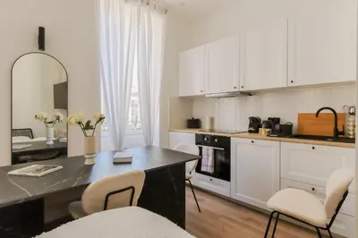a kitchen with white cabinets and a table and chairs at Fancy 3BR Duplex Near Nice Port & Old Town | By Airnest in Nice