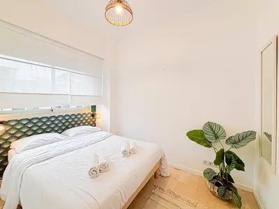 a bedroom with a bed with white sheets and a plant at Plage, Promenade & confort - Wifi, AC, 4 pers in Nice
