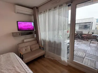 a bedroom with a large window with a tv and a chair at Beau Studio avec belle terrasse au centre ville de Nice in Nice