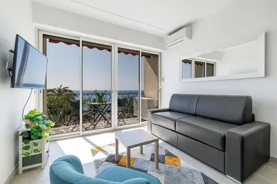 a living room with a black leather couch and a tv at Sea View - Lovely Studio Promenade des Anglais in Nice