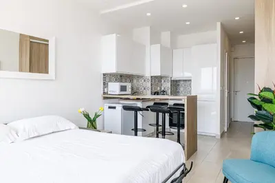 a white bedroom with a bed and a kitchen at Sea View - Lovely Studio Promenade des Anglais in Nice