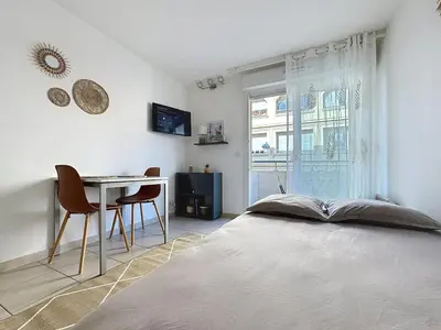 a bedroom with a bed and a table and a window at Studio calme avec balcon proche du port de Nice in Nice