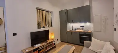 a living room with a television and a kitchen at Très joli 2 pièces à côté de l'AC Hotel Marriott Nice in Nice