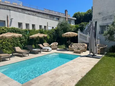 a swimming pool with chairs and umbrellas next to a building at maison de charme piscine au bord de mer in Cagnes-sur-Mer