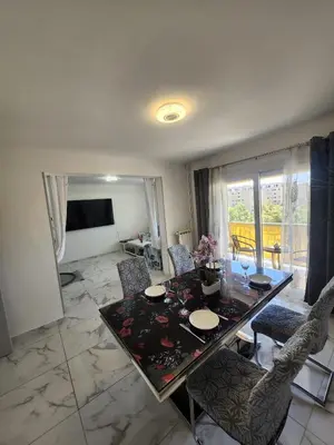 a living room with a dining table and chairs at Spacieux 3 chambres et balcon in Nice