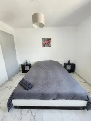 a bedroom with a large bed in a white room at Spacieux 3 chambres et balcon in Nice