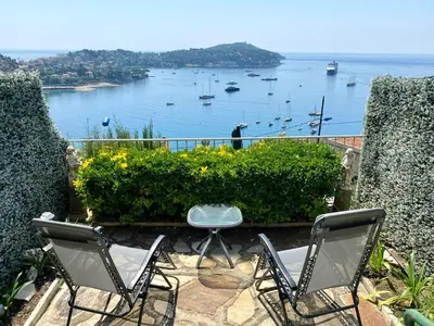 a couple of chairs sitting on a patio overlooking the water at Studio Bellevue in Villefranche-sur-Mer