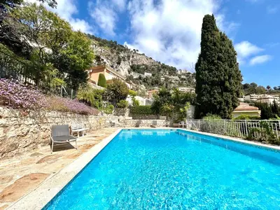 a swimming pool in front of a house with a mountain at Studio Bellevue in Villefranche-sur-Mer