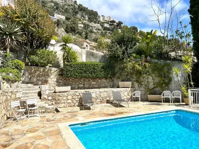 a swimming pool with chairs next to a stone wall at Studio Bellevue in Villefranche-sur-Mer