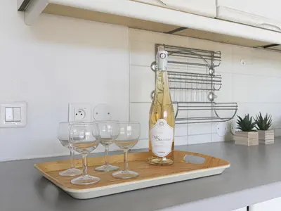 a bottle of wine and three wine glasses on a cutting board at Apartment Baie Azur by Interhome in Nice