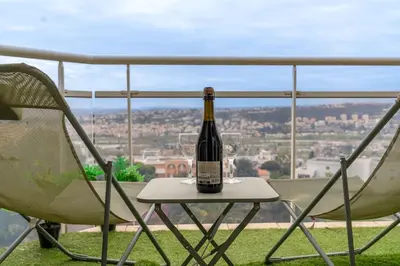 a bottle of wine sitting on a table with a chair at Studio équipé dans une résidence avec piscine à 10mn du centre ville in Nice