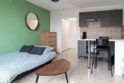 a bedroom with a bed and a table and a kitchen at Studio équipé dans une résidence avec piscine à 10mn du centre ville in Nice