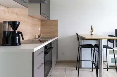a kitchen with a counter and a table with stools at Studio équipé dans une résidence avec piscine à 10mn du centre ville in Nice