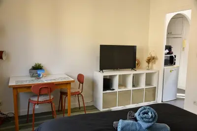 a living room with a tv and a table with a desk at Charmant studio moderne équipé à Nice in Nice