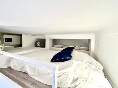 a white bed with a blue pillow in a bedroom at City Center Studio - 1 min Train Station & Main Street in Nice