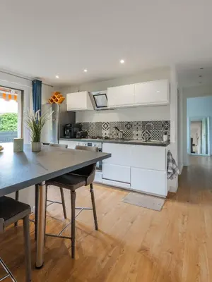 a kitchen with white cabinets and a wooden floor at Grand 2 pieces et belle terrasse ensoleillee in Nice