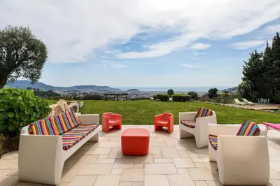 a patio with chairs and a table and a field at Magnifique villa avec vue mer panoramique in Nice