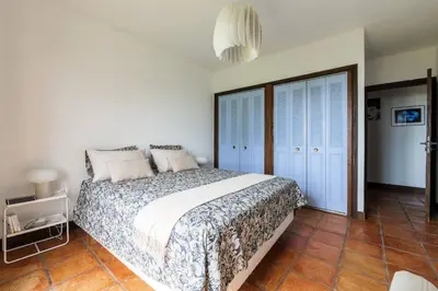 a bedroom with a large bed with blue shutters at Magnifique villa avec vue mer panoramique in Nice