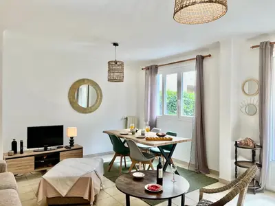 a living room with a table and chairs and a tv at Les Bleuets in Cagnes-sur-Mer