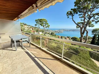 a table on a balcony with a view of the water at Les Jardins de Villefranche in Villefranche-sur-Mer