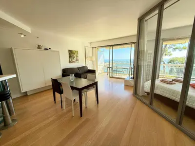 a living room with a dining room table and a bedroom at Les Jardins de Villefranche in Villefranche-sur-Mer