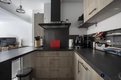 a kitchen with wooden cabinets and a black counter top at Air-conditioned apartment near Libération district in Nice
