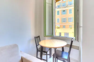 a table and chairs in a room with a window at LYMPIA -Cosy studio, 200 m plages de Nice - Le Port in Nice