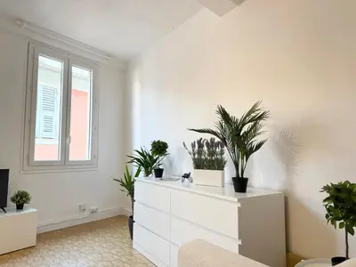 a white living room with plants on a dresser at Charmant 2 pièces proche mer in Nice