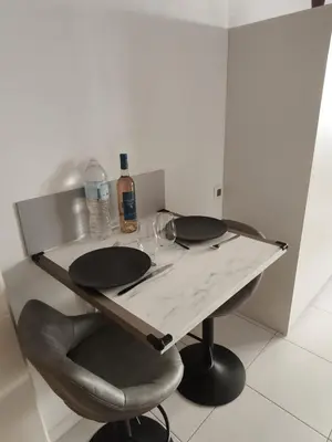 a table with a chair and a bottle of wine at Studio calme et paisible, climatisé avec terrasse au dernier étage, 100m du tramway et 20 min de la promenade des anglais in Nice
