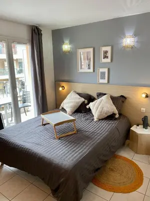 a bedroom with a large bed with a table on it at Charming studio with swimming pool in Nice