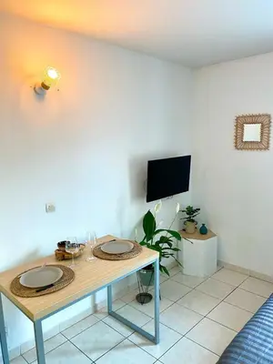 a table with two glasses and a tv in a room at Charming studio with swimming pool in Nice